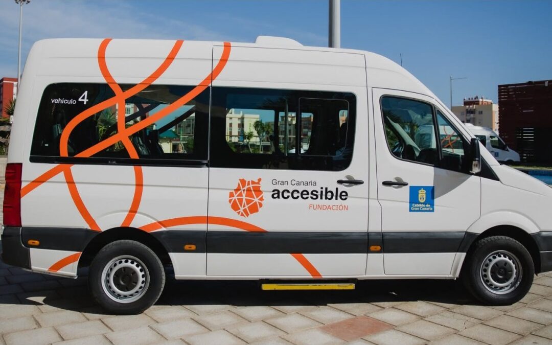 Guagua blanca de la Fundación Gran Canaria Accesible, con gráficos naranjas y el logotipo de la entidad y del Cabildo de Gran Canaria, estacionada en una zona urbana.